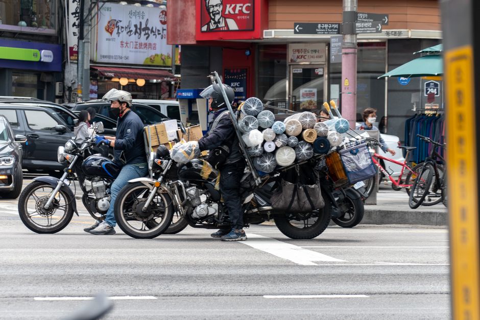 motorcyclists waiting with cargo at a Seoul intersection