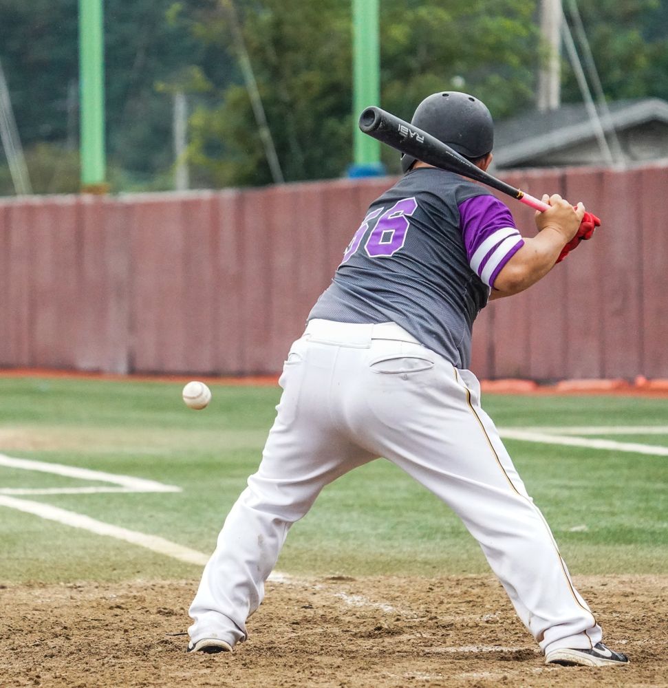 baseball batter mid-swing at a Korean baseball field with a fielder wall behind home plate