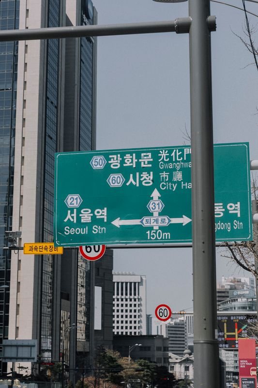 Korean street signs with road names in a downtown Seoul setting