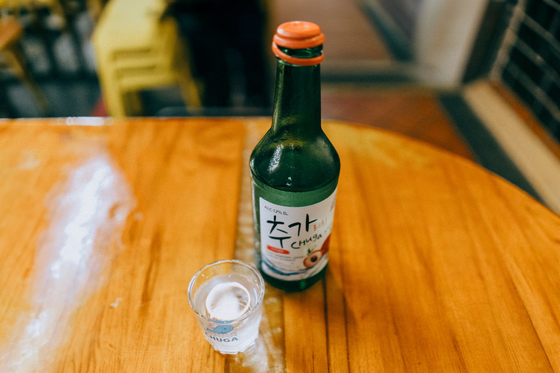 Soju bottle and shot glass on a wooden table in a Korean restaurant