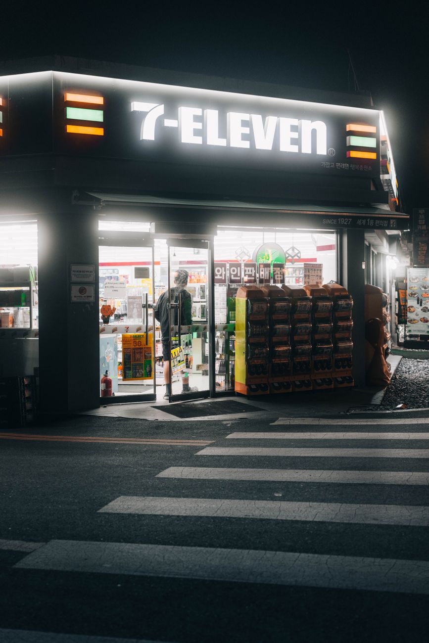 A 7-Eleven storefront lit up at night in Seoul, South Korea