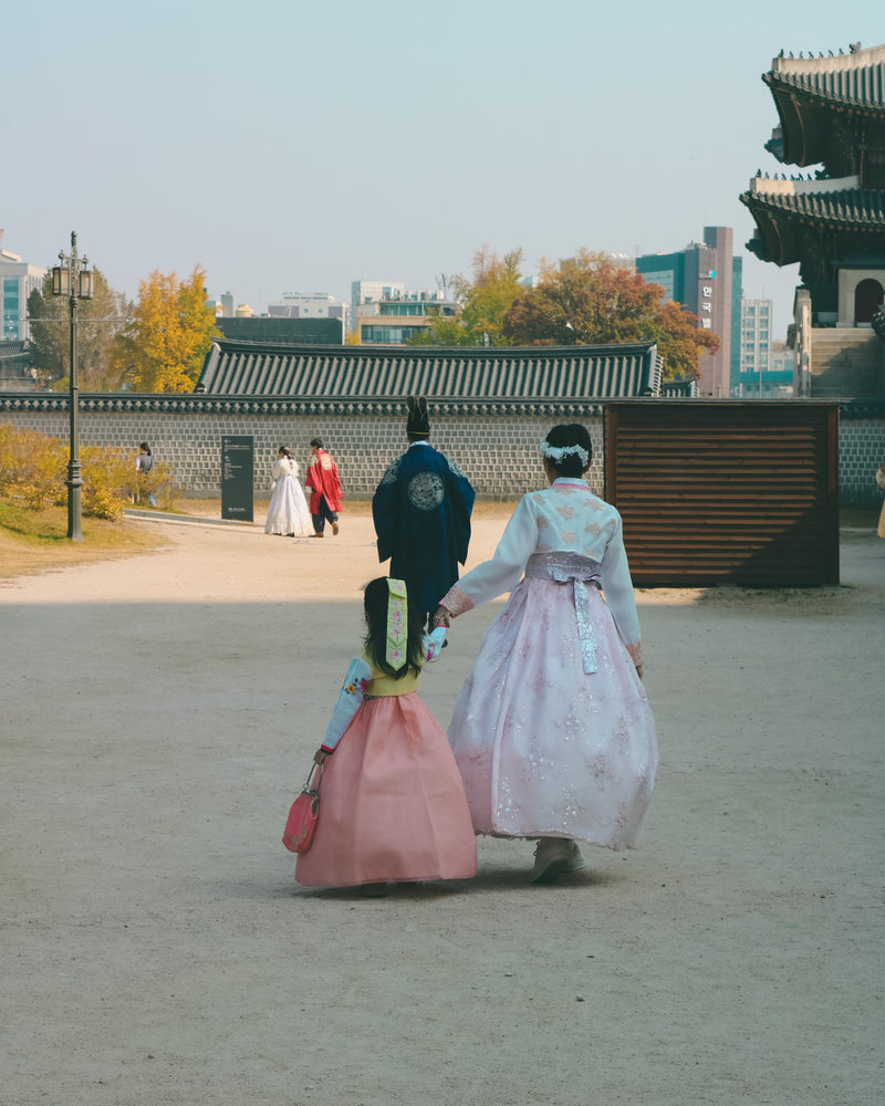 Mother and child in hanbok walking in a Seoul park during autumn