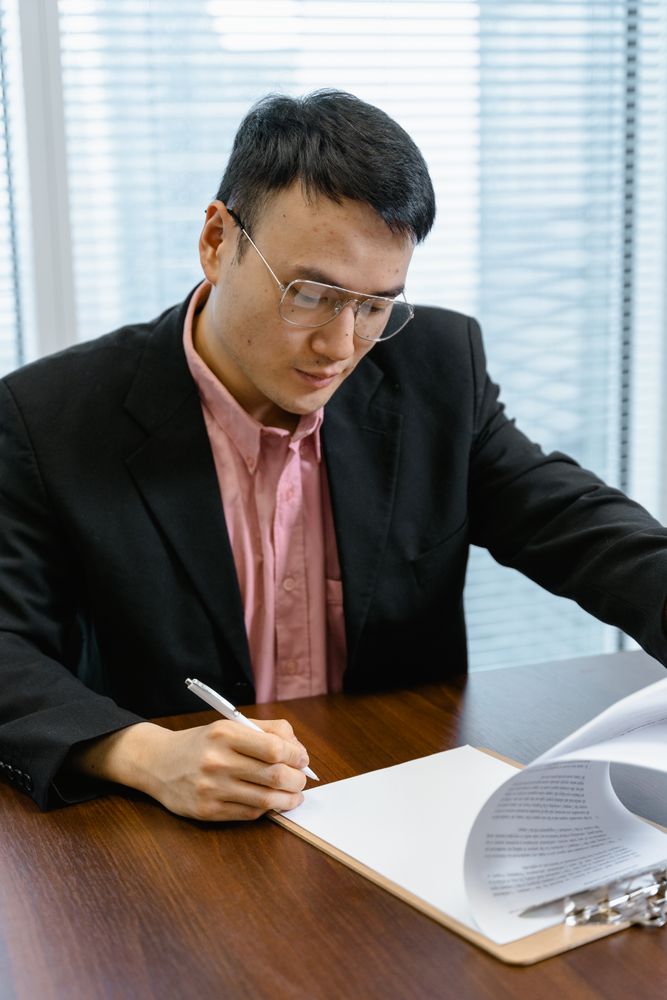 An office employee in a suit reviewing paperwork at his desk
