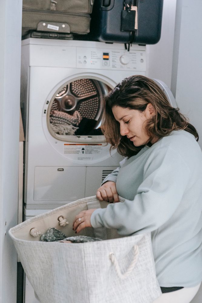 A woman doing laundry indoors, representing the etiquette of running washing machines only during daytime hours in Korean apartments