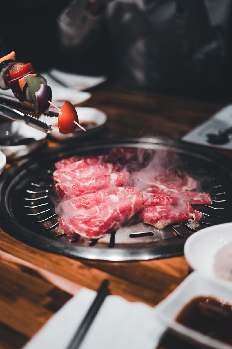 Grilled Korean barbecue meat sizzling on an indoor grill with side dishes on the table