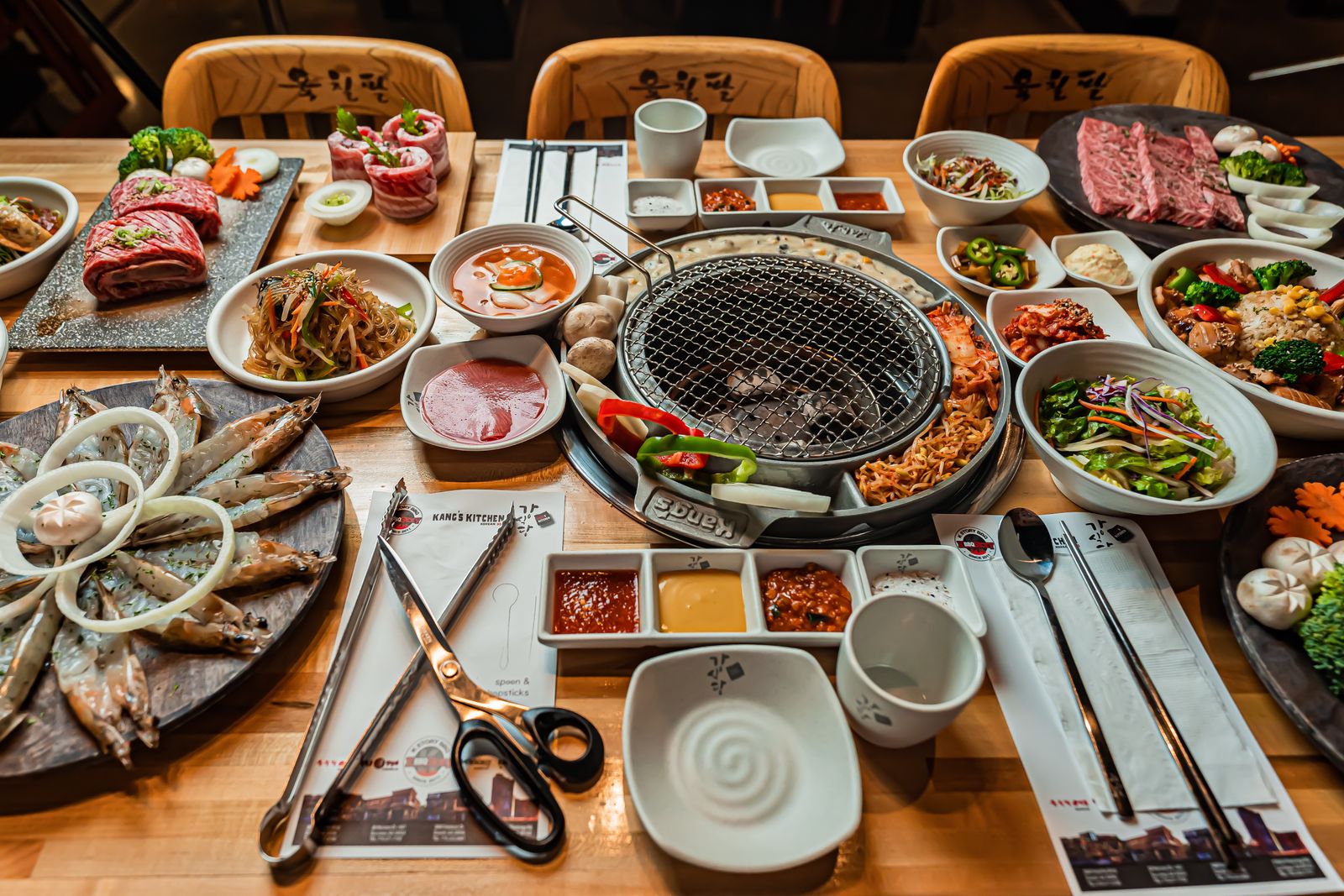 Korean barbecue dinner table set up for a group hoesik with grill and side dishes