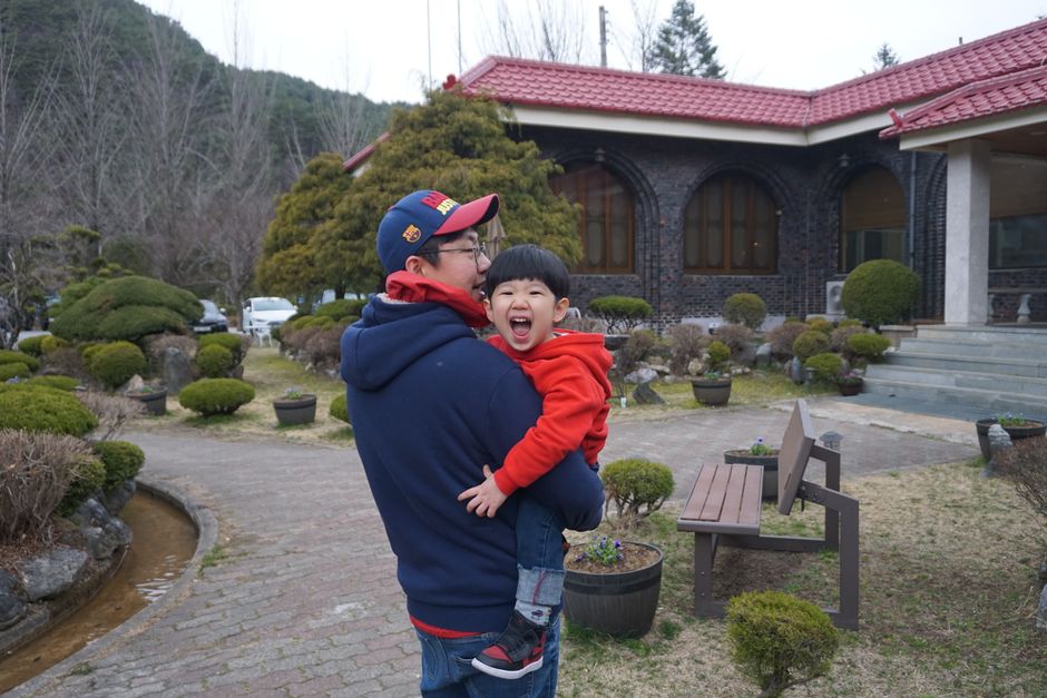 Korean father holding his laughing son outside a traditional building