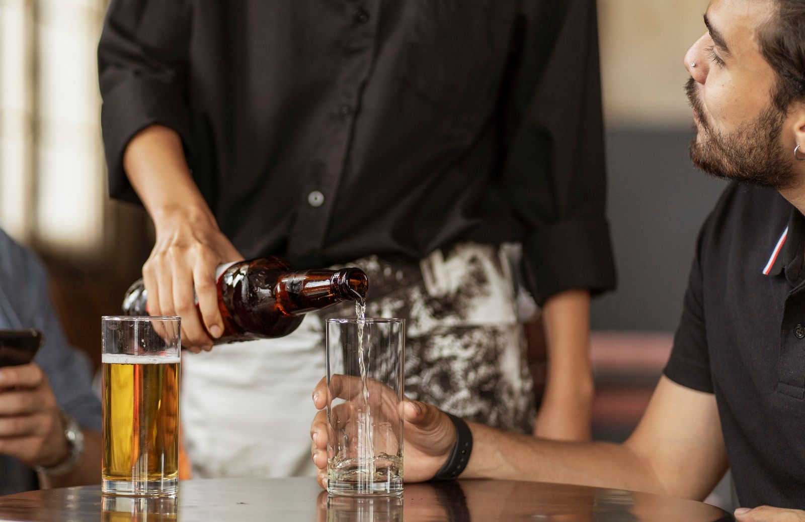A man pouring a drink for someone at a restaurant table in Korea