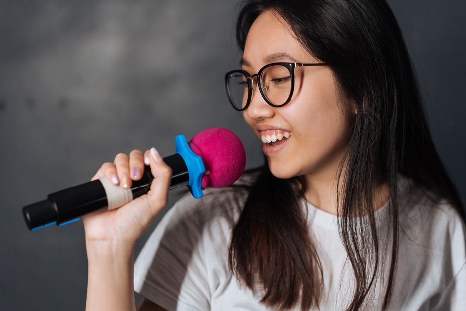 A young woman singing passionately into a microphone at a noraebang session