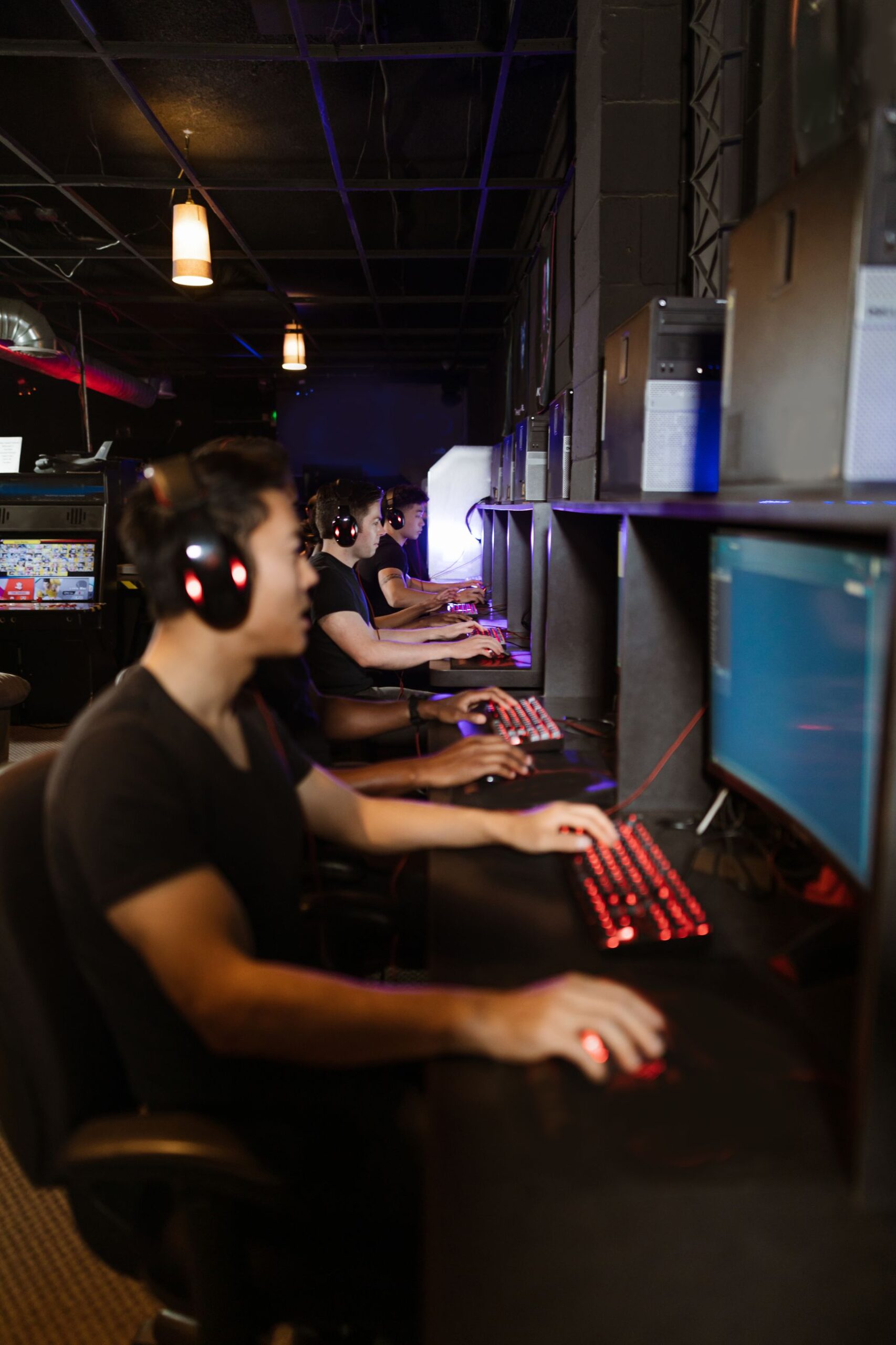 A group of young adults wearing headphones and gaming together in an internet cafe