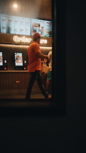 Customers using self-service ordering kiosks in a fast food restaurant