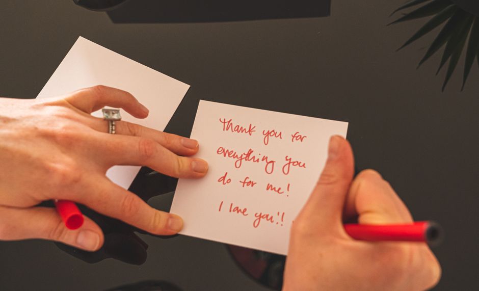 A hand writing with a red pen on paper