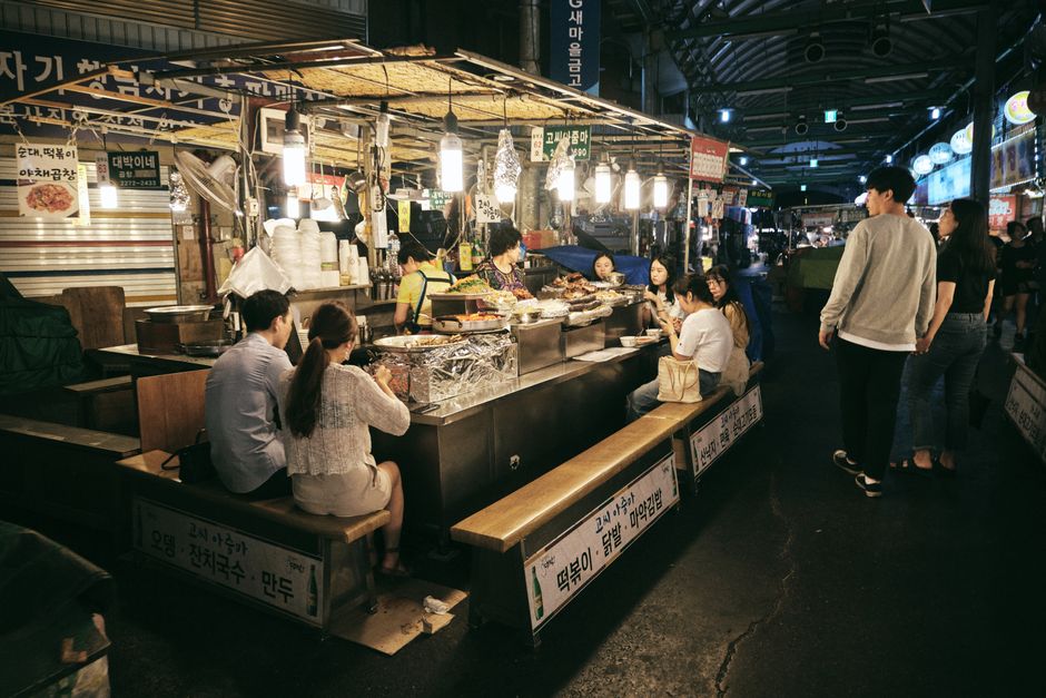 Crowd of people walking through a night market with food stalls in Seoul