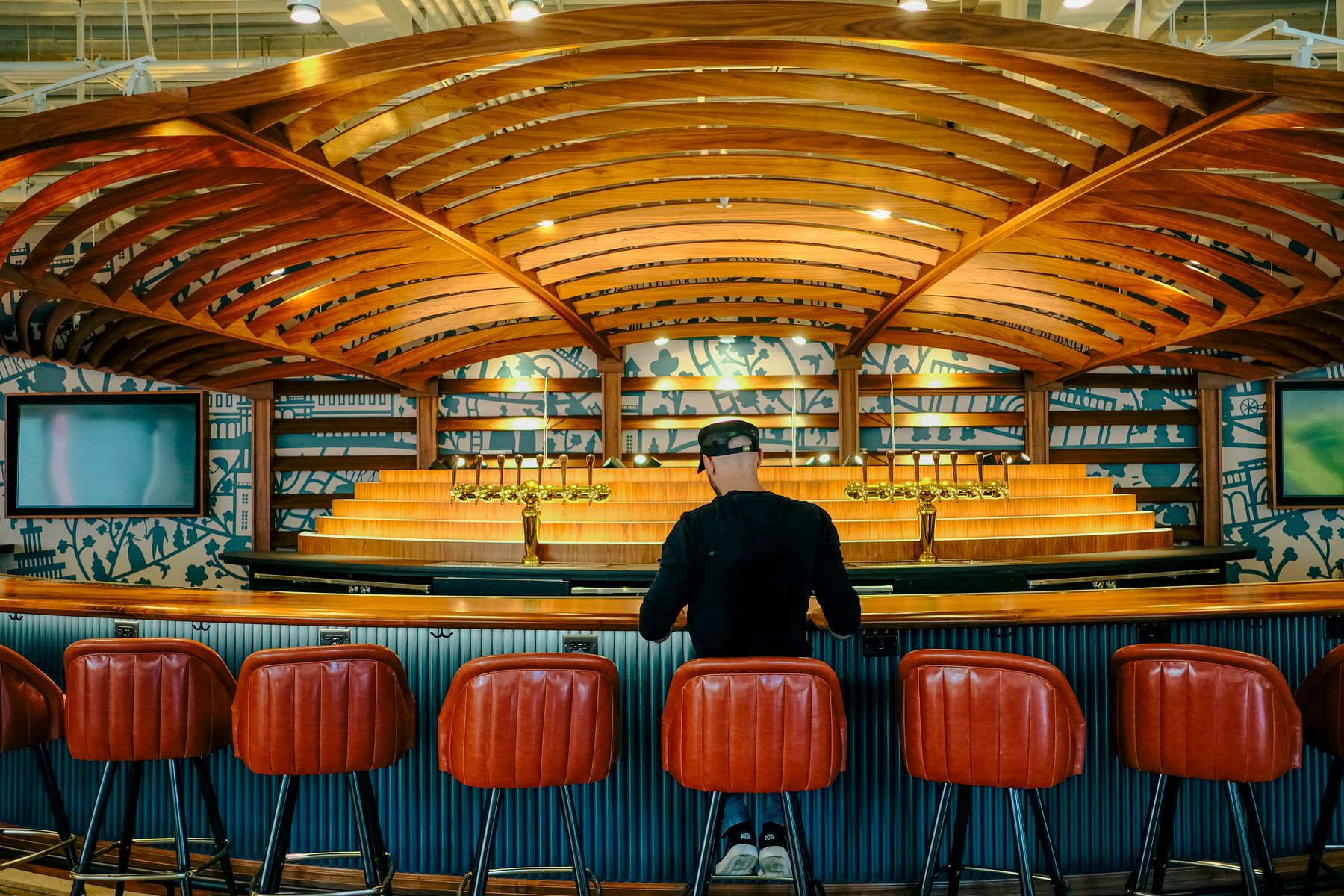 A single person seated alone at a stylish bar counter with warm lighting